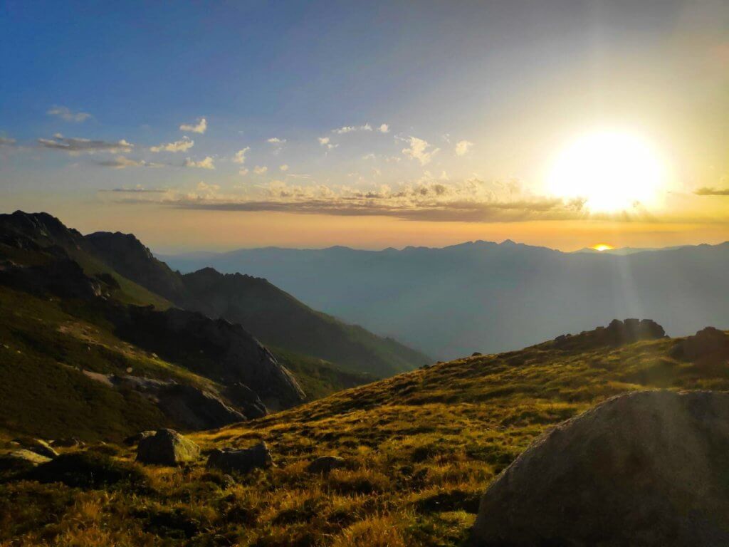 Coucher de soleil sur les crêtes du Jura, pelouse d'altitude et vallée noyée dans la brume.