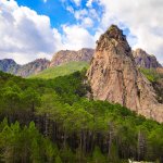 Aiguille de granite des Aiguilles de Bavella dressée au-dessus de la forêt de pins sur le GR20 en Corse