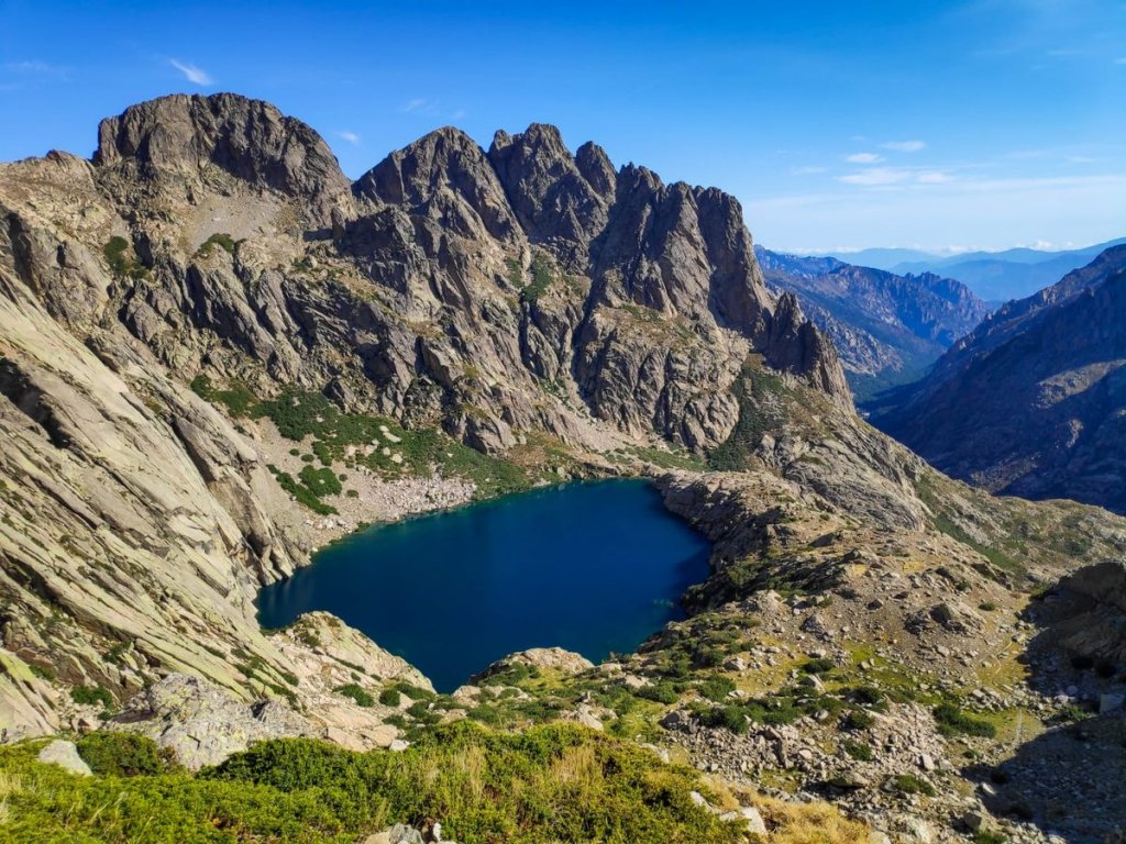 Lac de montagne aux eaux profondes encadré de parois rocheuses sur le GR20 en Corse