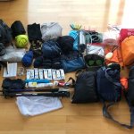 Matériel de randonnée disposé au sol pour préparer le sac à dos du GR20 : équipement de trek et affaires de bivouac